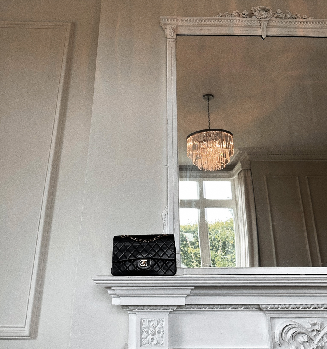 Pre-loved vintage Chanel Black Quilted Lambskin Medium Classic Double Flap Bag on an impressive fireplace in manor house.